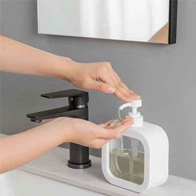 distributeur de savon blanc deux mains versent savon transparent sous miroir
